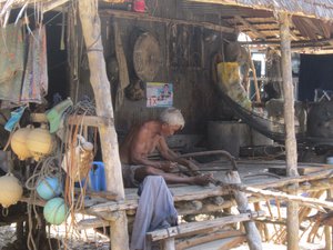 An old man sawing wood in his house in one of the little villages on Koh Jum