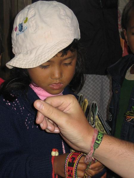 Lat tribe kid tying a tatty bracelet to Eds arm