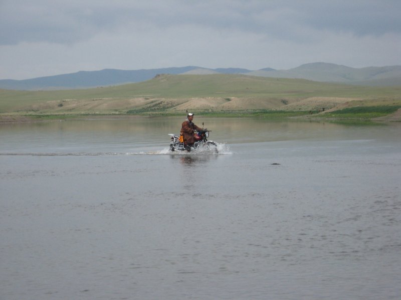 Herder crossing the river on motorbike!