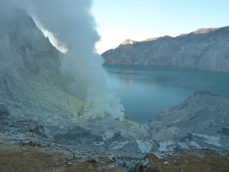 The fizzure billowing acrid steam next to the acidic crater lake in the morning light