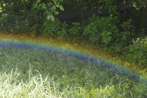 Regenboog boven het gras door opspattend water