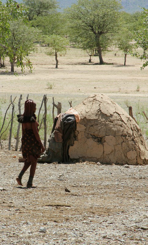 Himba lady and mud house