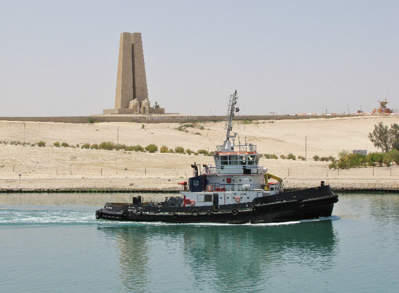 1304-369 A pilot boat returning in front of memorial honoring early 19th century defenders of the canal and Egypt