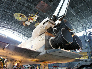 1307-54 The space shuttle, Discovery with satellites overhead