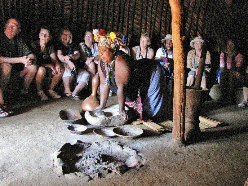 1403-272 Zulu Park--Woman tells about cooking hut--note corn metate and mano--we wondered how long before corn artrived from South America