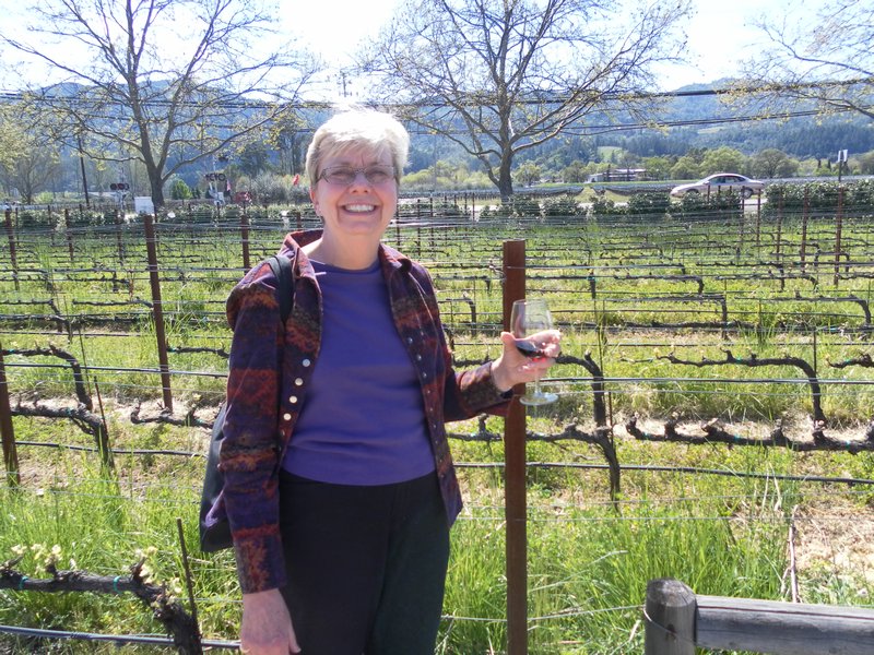 Mom drinking a glass of wine and standing by the grapes it was made from!