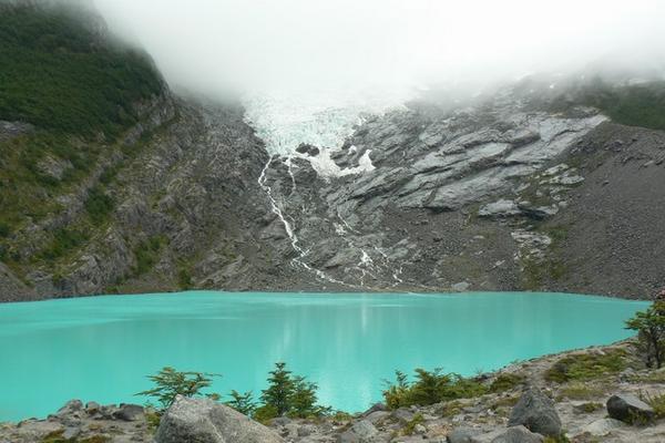 Cloud-shrouded Glaciar Huemul and its lake