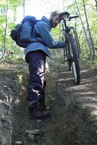 Dave carries his bike along a narrow track