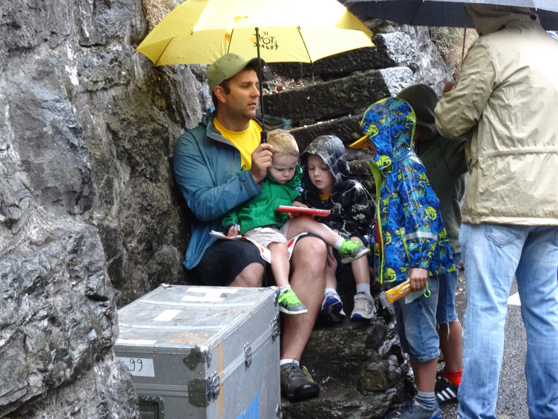 Kids surrounding Adrian to watch Peppa Pig on the tablet in the rain