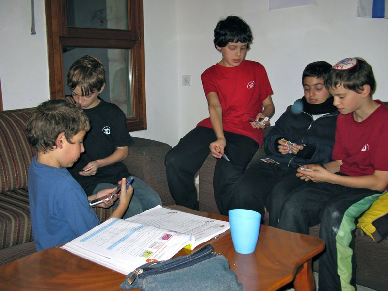 Ezra with friends Ameetie and Yonatan compare Supergol cards while Ameet chats on his cell phone