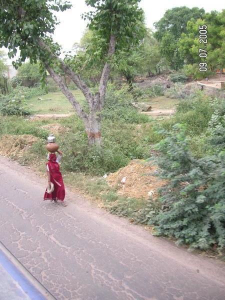 Woman in Burka carries bowl on head