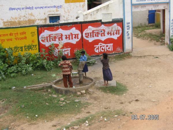 Kids on side of road work the water pump