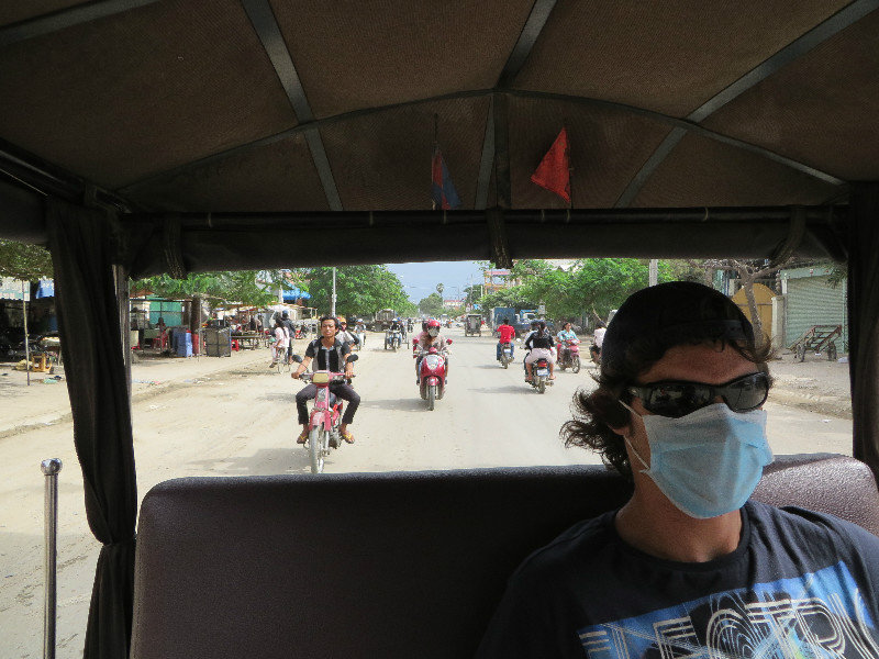 Con mascarilla y gafas para evitar el polvo y el humo de Phnom Penh
