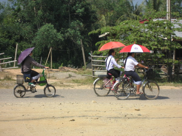 Riding Bikes with umbrellas to cut out the sun