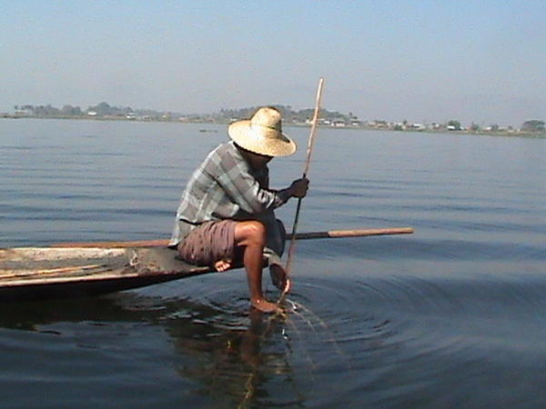 Inle Lake fisherman with foot securing net to lake bottom.....whilst he stabs anything that moves with his trident-like thingy.... 