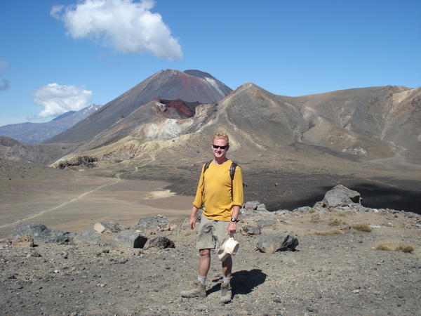 Me pausing for breath after our climb down from the red crater in the background - Tongariro Crossing