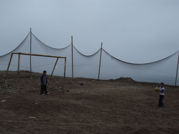 Boys playing football in forlorn surroundings at a shanty town on the outskirts of Miraflores