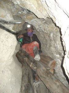 Helen clambers down a shaft on logs on our mine tour