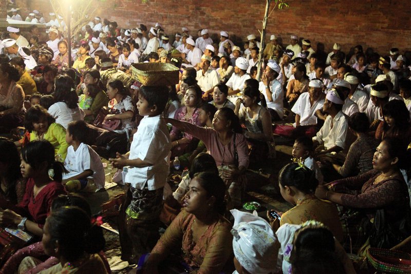 Seated worshippers sit among the trees in the temple