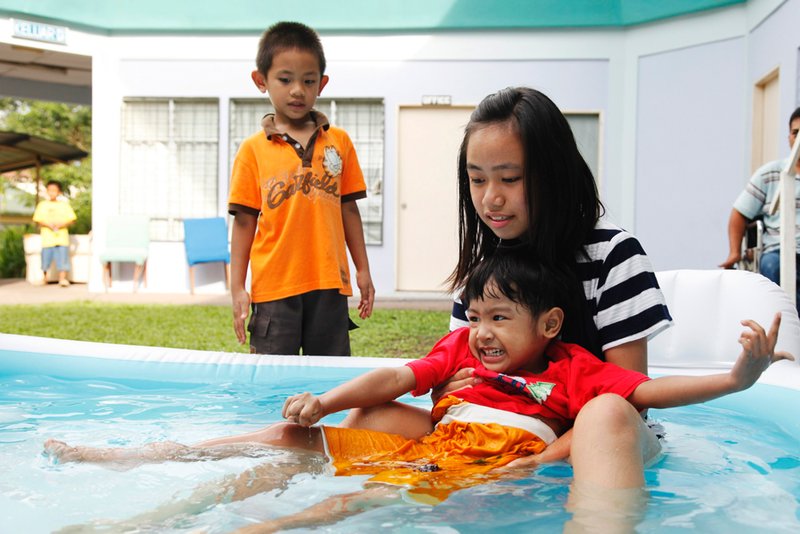 Gladys helping Nurul Rafiqah (aka Fifi) in the paddling pool while Ah Pui watches.