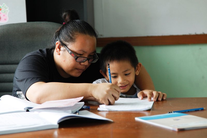 Teacher Jennet helps Ah Pui with some schoolwork.