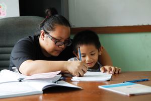 Teacher Jennet helps Ah Pui with some schoolwork.