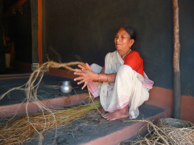 Village - femme tressant une corde d'herbes