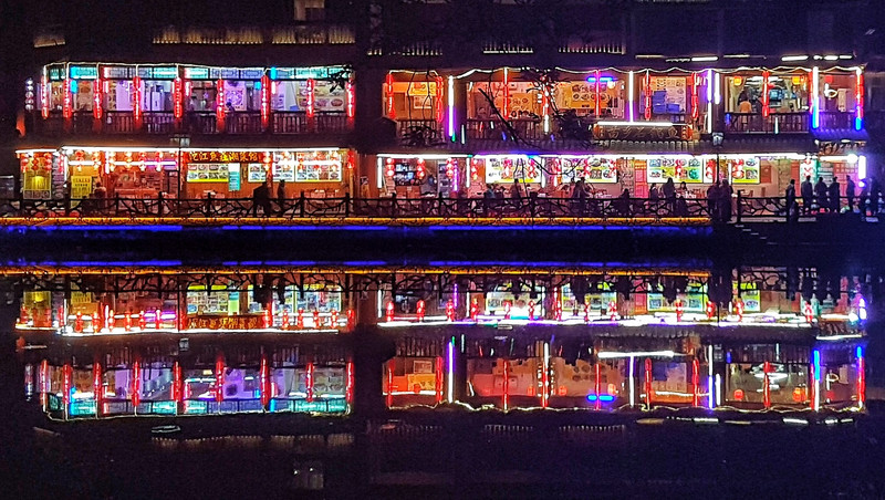 Neon signs reflected in the river in Fenghuang 