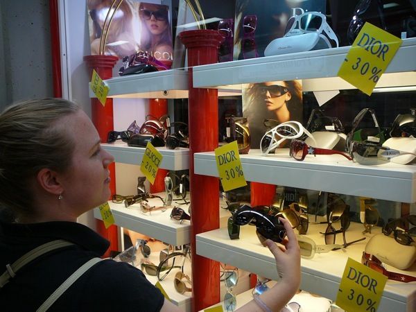 Alicia Comparing the Fake Sunnies We Bought From a Street Vendor to the Real Ones in a Shop Window