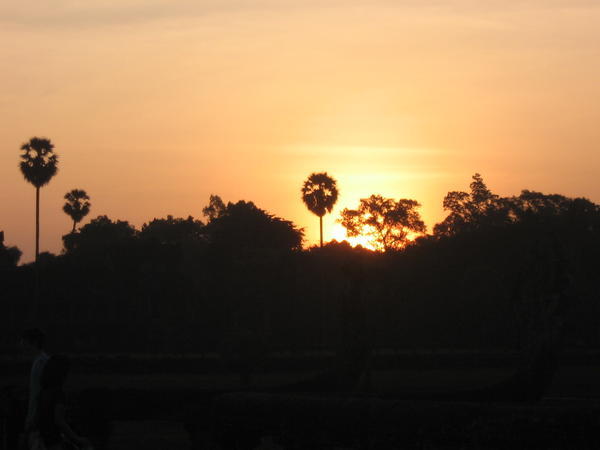 The sun peeks over the trees of Angkor Wat