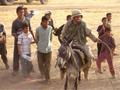 Nathan entertains Iraqi children atop a donkey