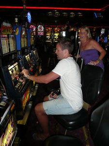 Andrew playing slots, Laura messin' around behind him.