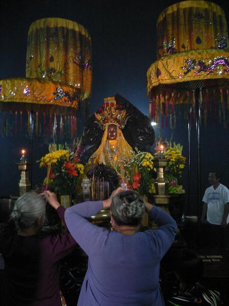 People praying to a tacky looking buddha inside