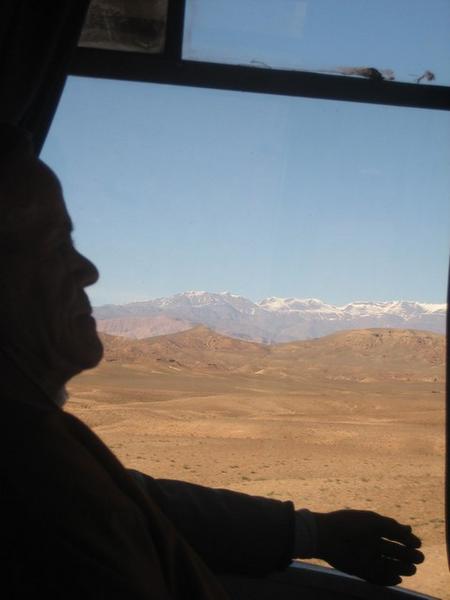 Profile of old man on the bus to Fes with the Atlas Mountains in the background