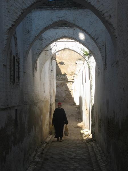 An old man walking through one of the myriad passages in the Medina