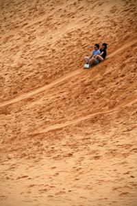 poeple having fun sliding on the dunes...