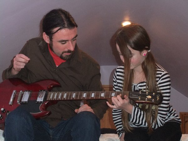 Kris teaching Elisha, his niece, to play guitar