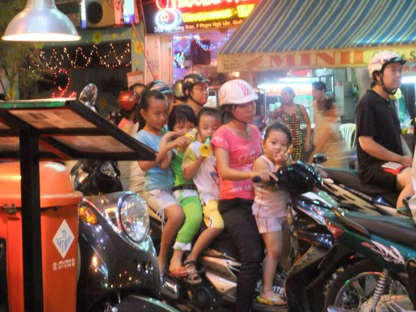 4 kids on a motorbike. Only Mum wears a helmet