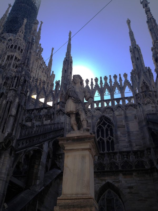 Saint on the roof of the duomo with the sun behind him