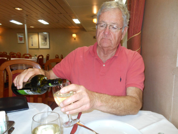 Gary pouring wine in dining room on ferry