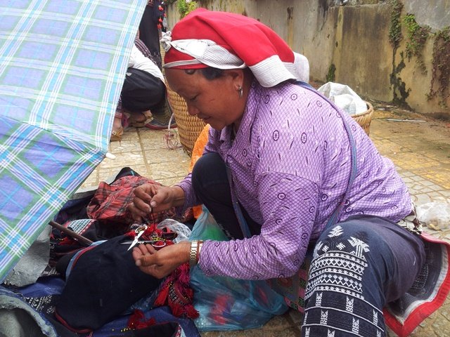HMong lady sewing tassles on