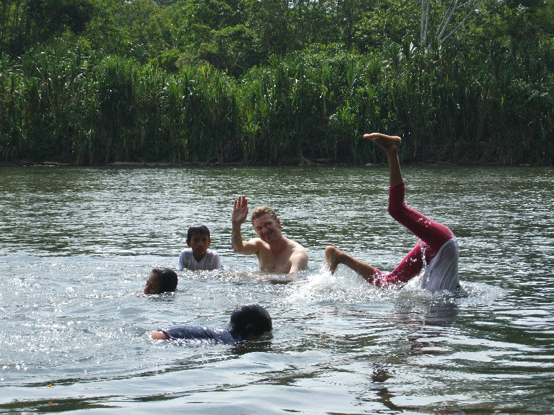 while swimming in the river, local kids came from school by canoes and took a swim too