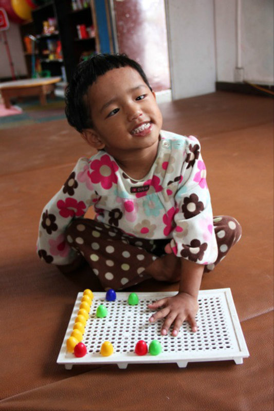 One of the Special Education Rehabilitation Centre's (SERC) orphan children enjoying her physiotherapy, Kathmandu, Nepal