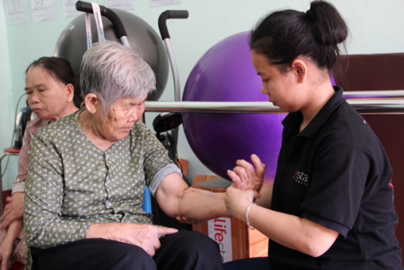 Thuyet helping one of the more elderly residents with her elbow pain.