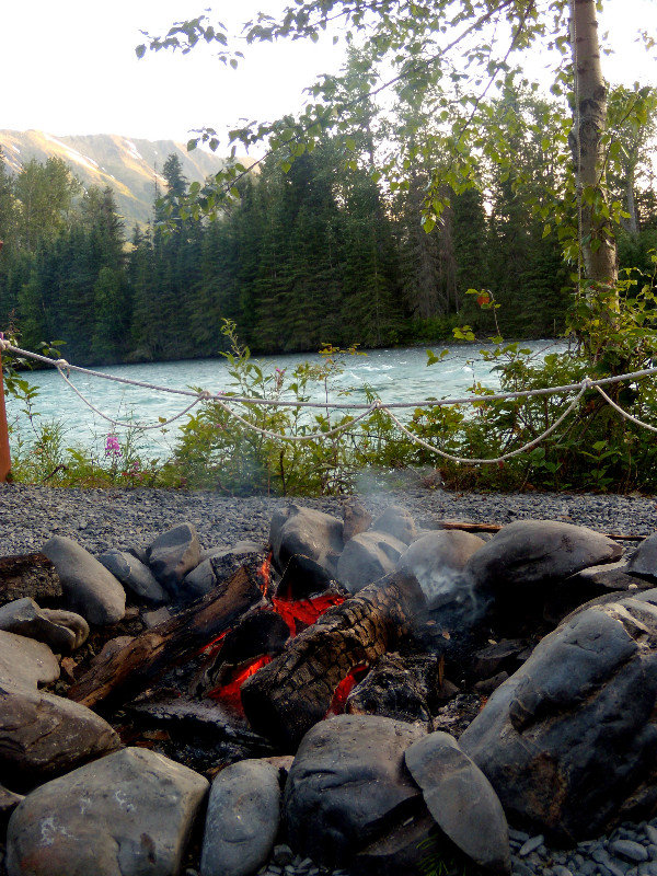 Campfire along the river with mountain backdrop 