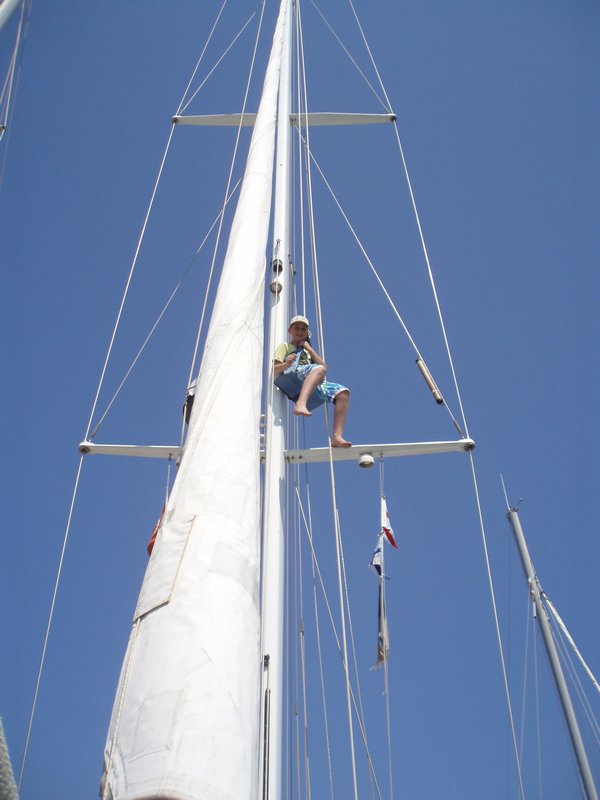 Cameron up the mast tying on the ARC flag