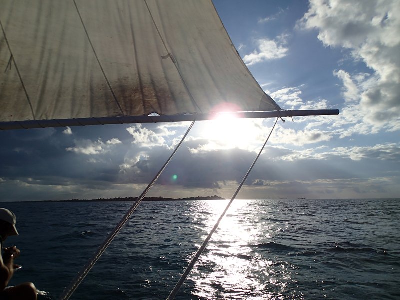 Sail unfurled and sun setting.