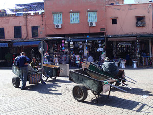 These men are waiting for people to purchase things and they will use these carts to transport them from the market.  