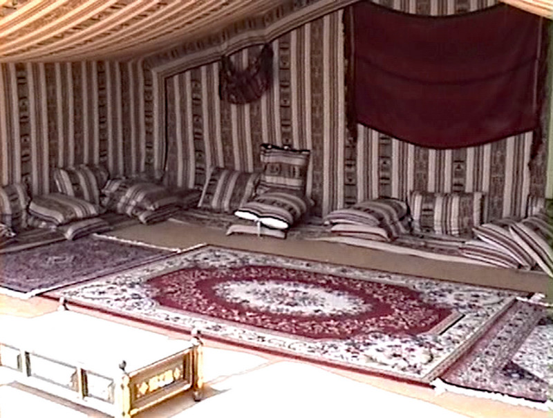 Tent furnished with rugs, cushions, and hangings