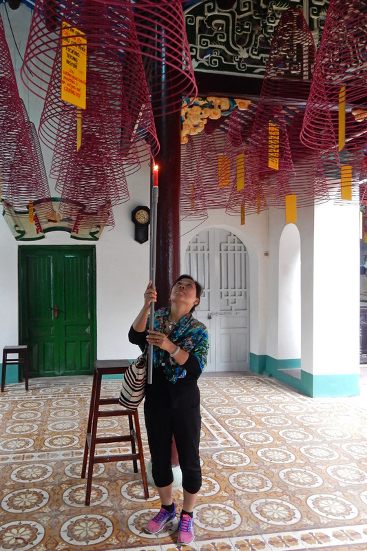 Thuy worships by lighting a hoop of incense.